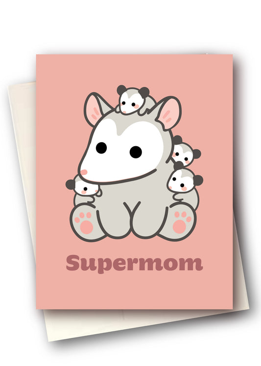 A pink greeting card featuring a cute cartoon aardvark with several small panda cubbies around it, and the word 'Supermom' printed below. The card is shown layered over a cream envelope on a white background.