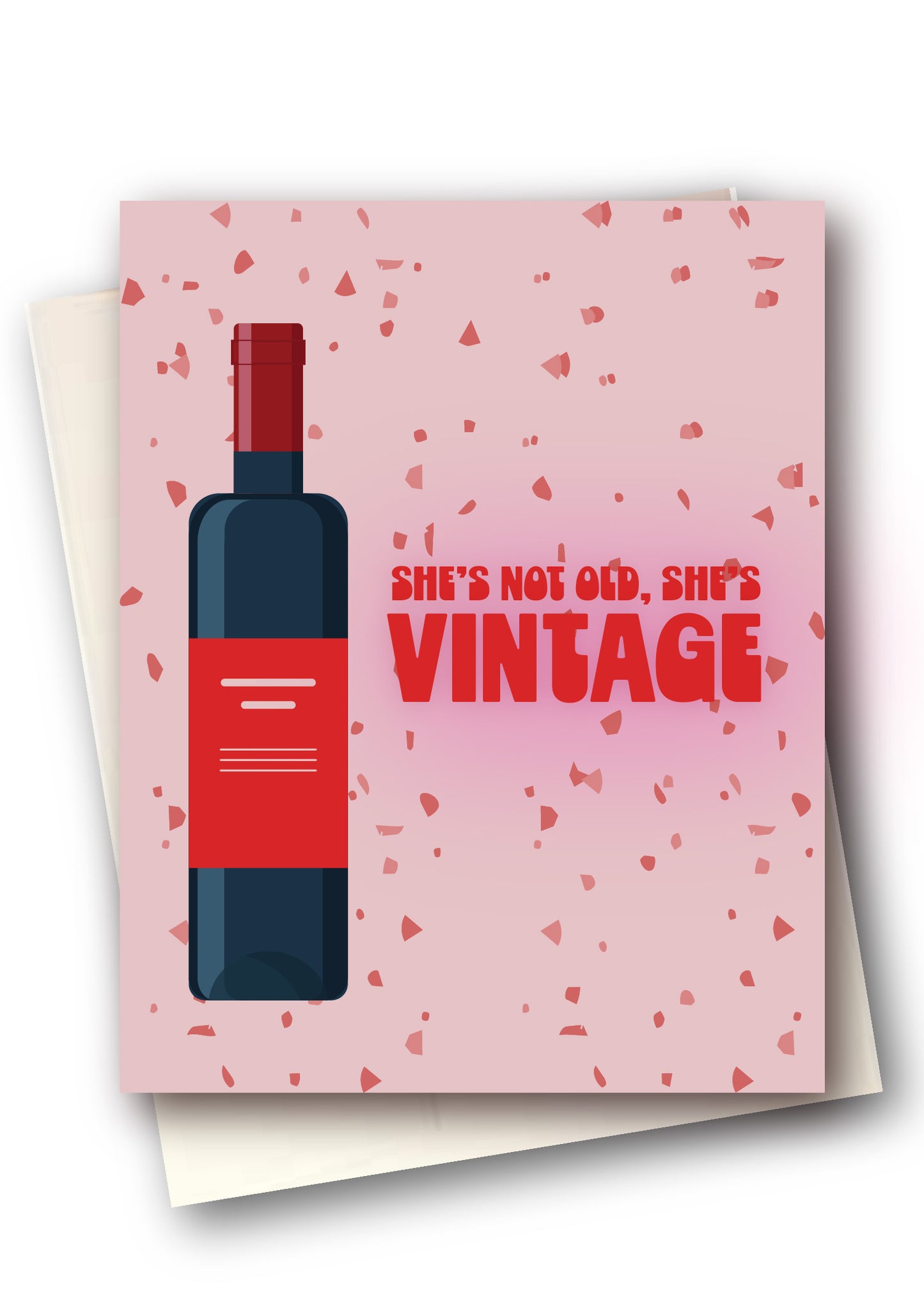 A pink greeting card with a red wine bottle illustration and the text 'SHE'S NOT OLD, SHE'S VINTAGE' in red, shown with cream envelopes behind it on a white background.