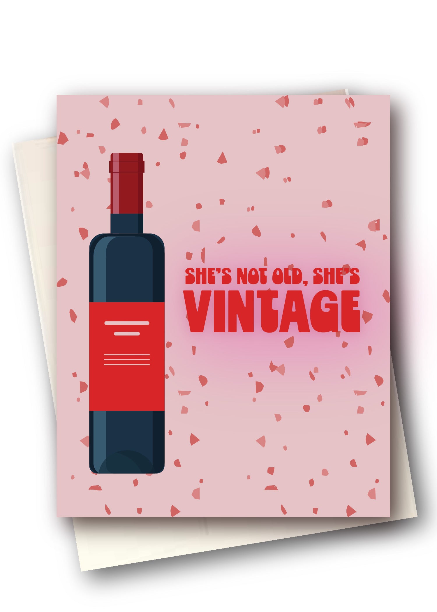 A pink greeting card with a red wine bottle illustration and the text 'SHE'S NOT OLD, SHE'S VINTAGE' in red, shown with cream envelopes behind it on a white background.